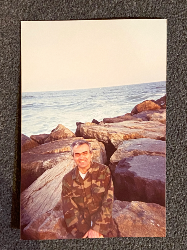 photo of Henryk Siwiak sitting on large rocks by the water