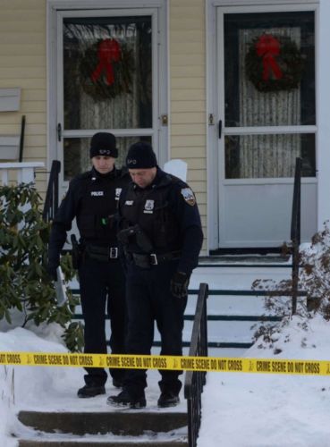 police officers walking from house surrounded by crime scene tape