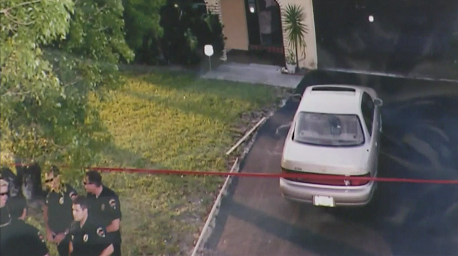 picture of car parked in front of house and police standing in front of crime scene tape